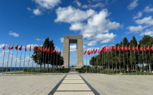 Gallipoli Monument with rows of Turkish flags under a bright blue sky.